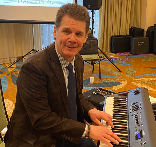 A man sits with his hands on an electric keyboard